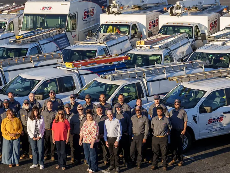 Spectrum Maintenance Services technicians and account staff in front of the company's commercial service fleet